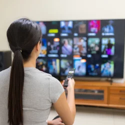 Woman choosing channels on Smart TV using IPTV Smarters 8k Pro subscription – best IPTV Smarters Player 2025.